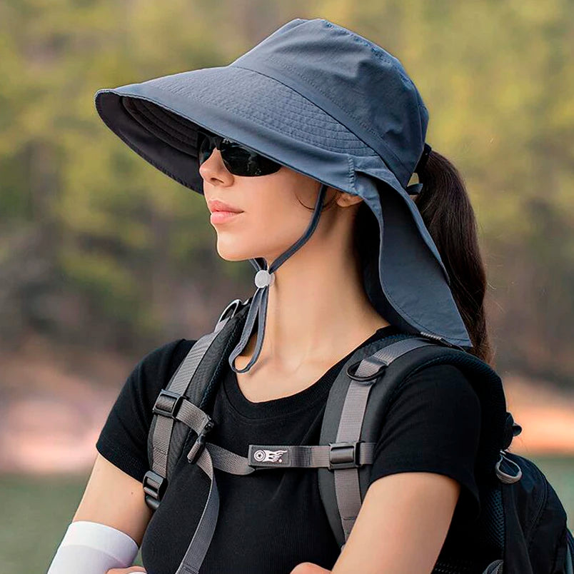 A girl with glasses wearing a dark gray SunShield Brim Sun Hat, enjoying a sunny day outdoors.